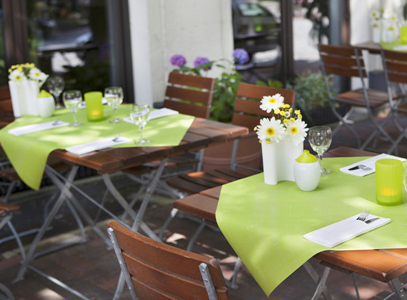 Outdoor restaurant tables set with green Dunisilk® table cover