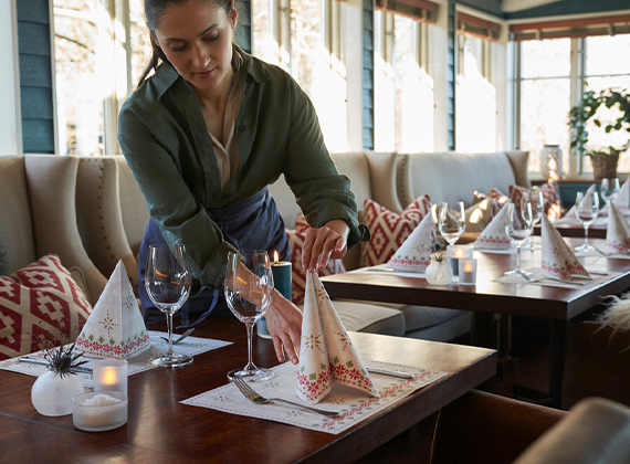 Restaurant table decorated with Christmas table settings with folded napkins and placemats